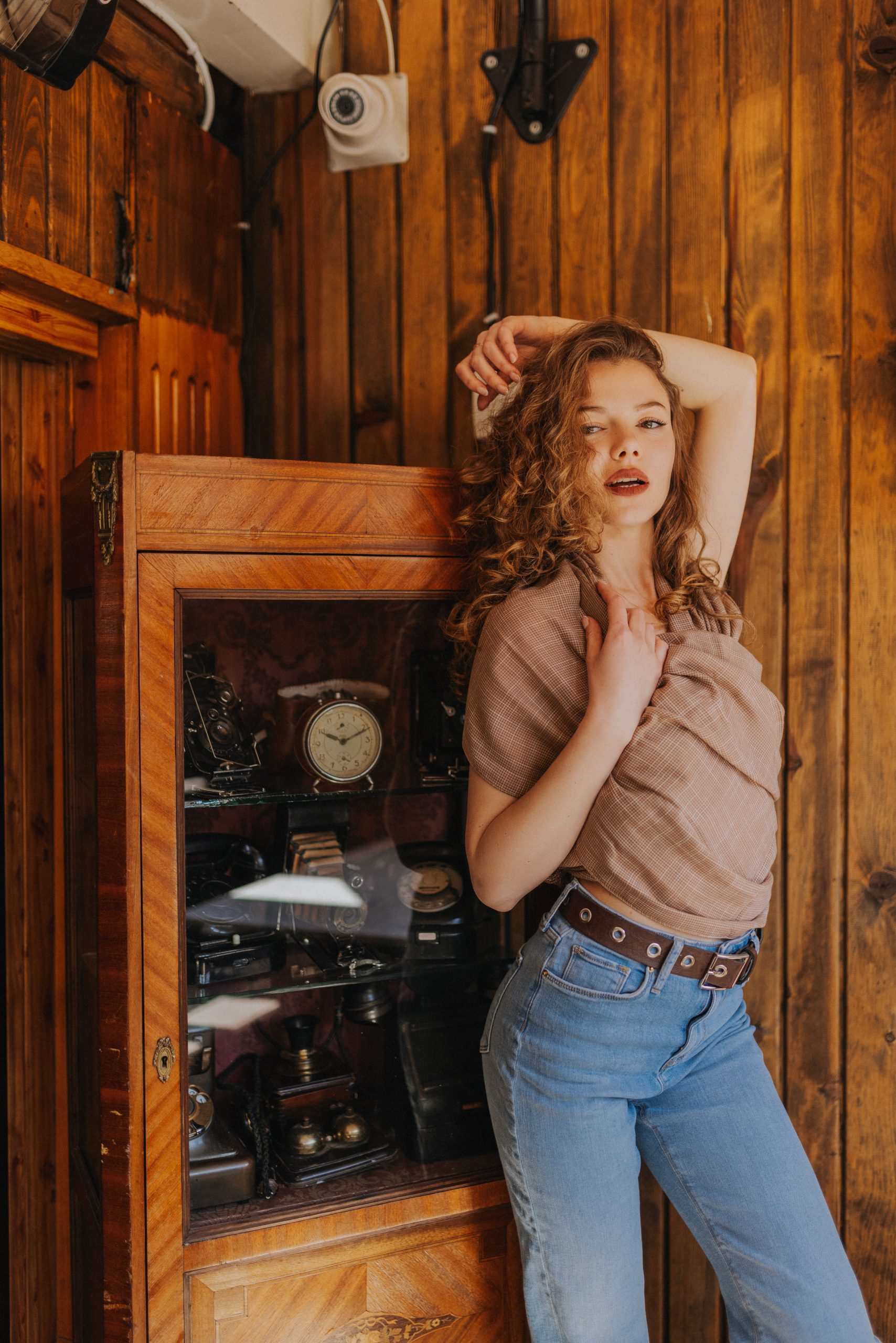 Woman wearing a brown blouse and jeans in a room with wooden furnishings