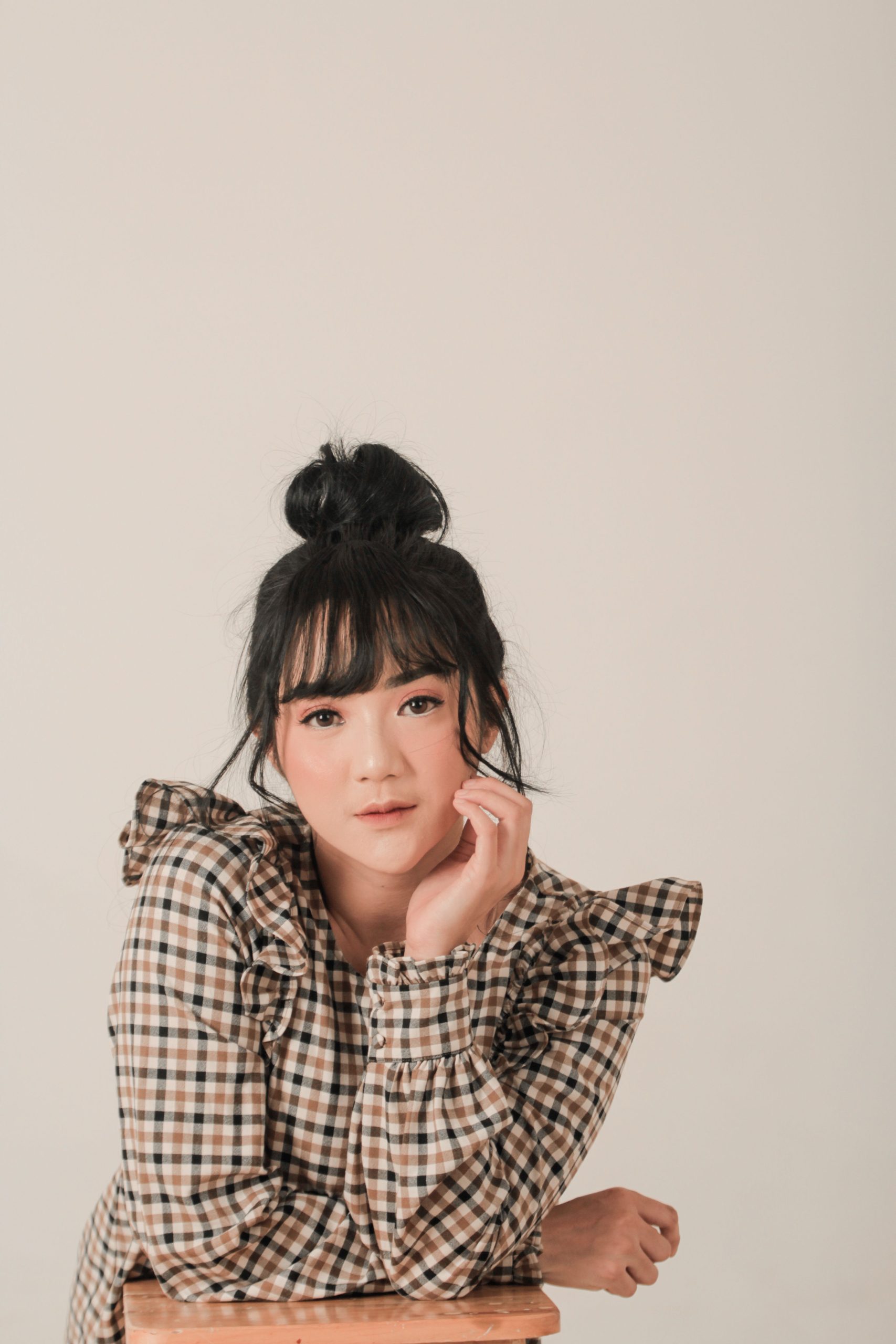 Woman modeling a checked blouse with ruffled details in a studio portrait