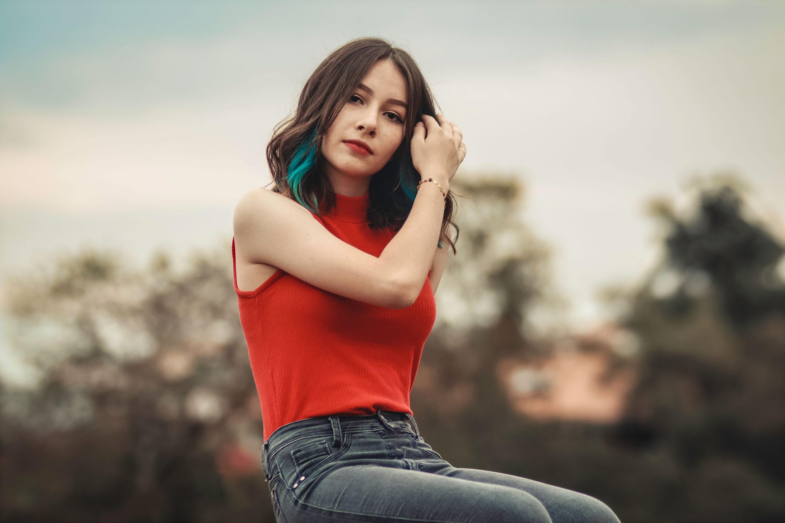 Woman wearing a red sleeveless blouse with dark jeans outdoors