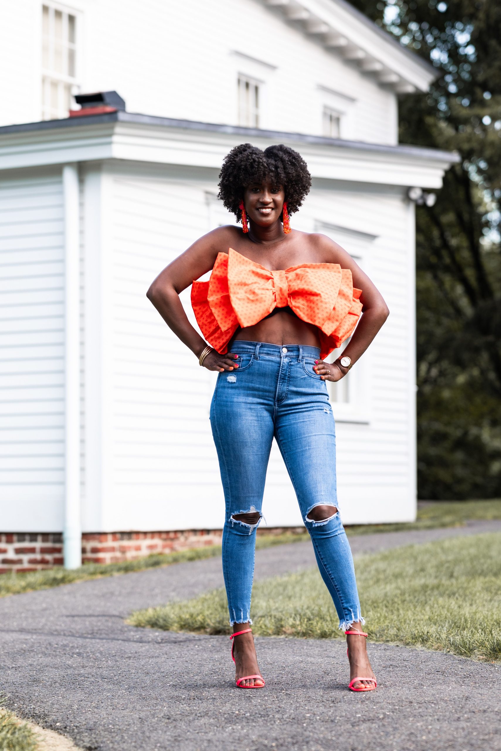 Woman wearing a vibrant statement bow top with denim jeans outdoors