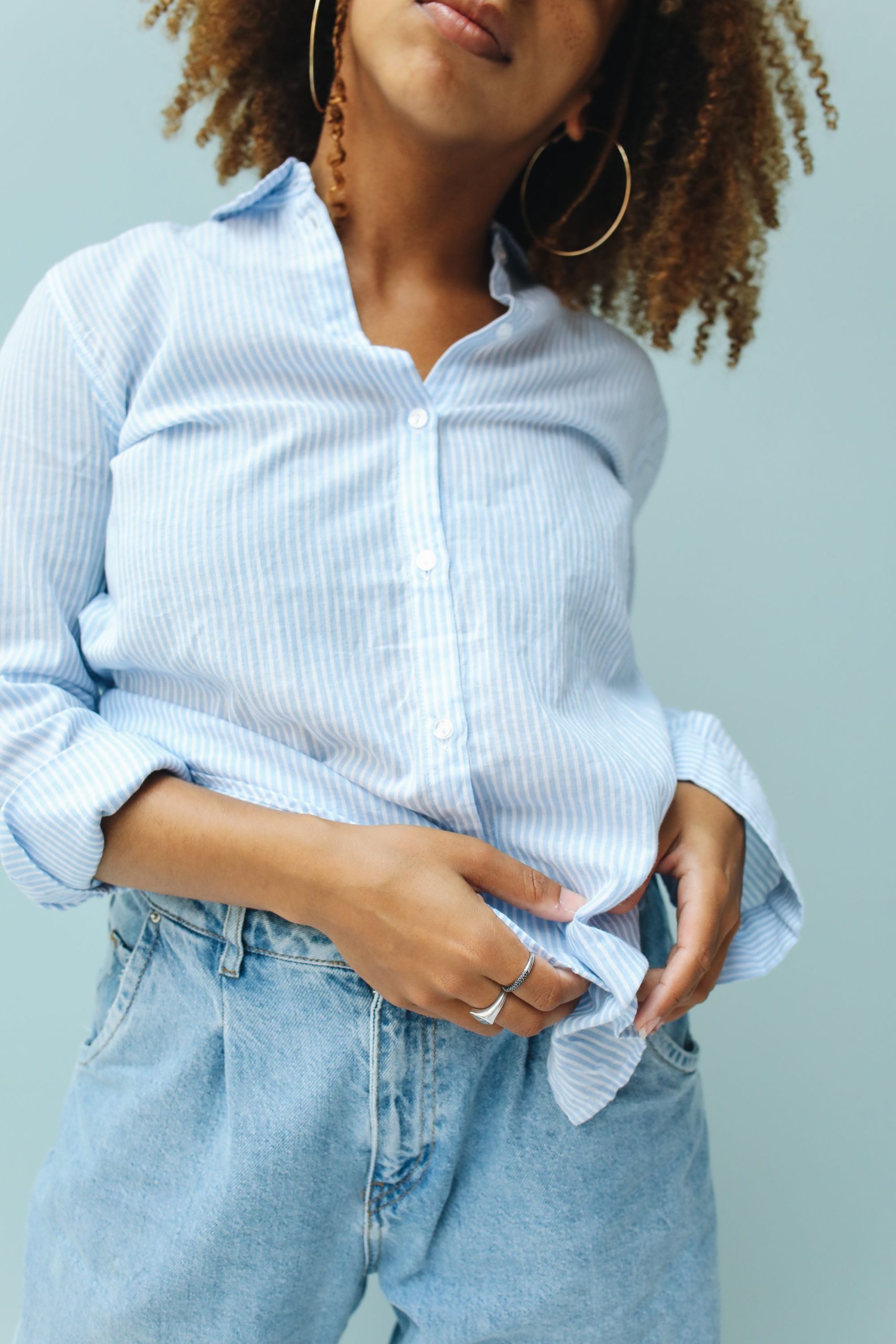 Woman wearing a blue and white striped long sleeve shirt with denim jeans