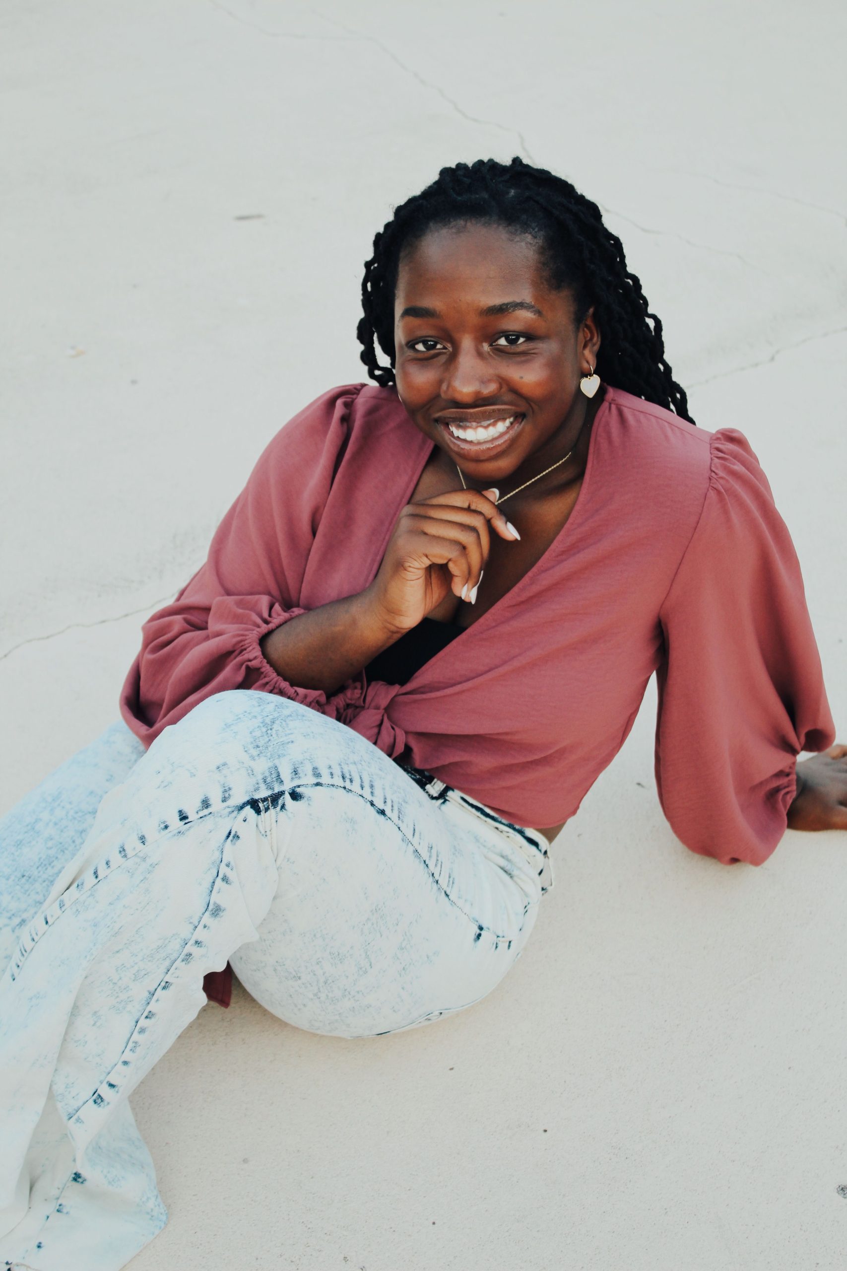 Woman wearing a pink tie front long sleeve cropped blouse and light wash jeans