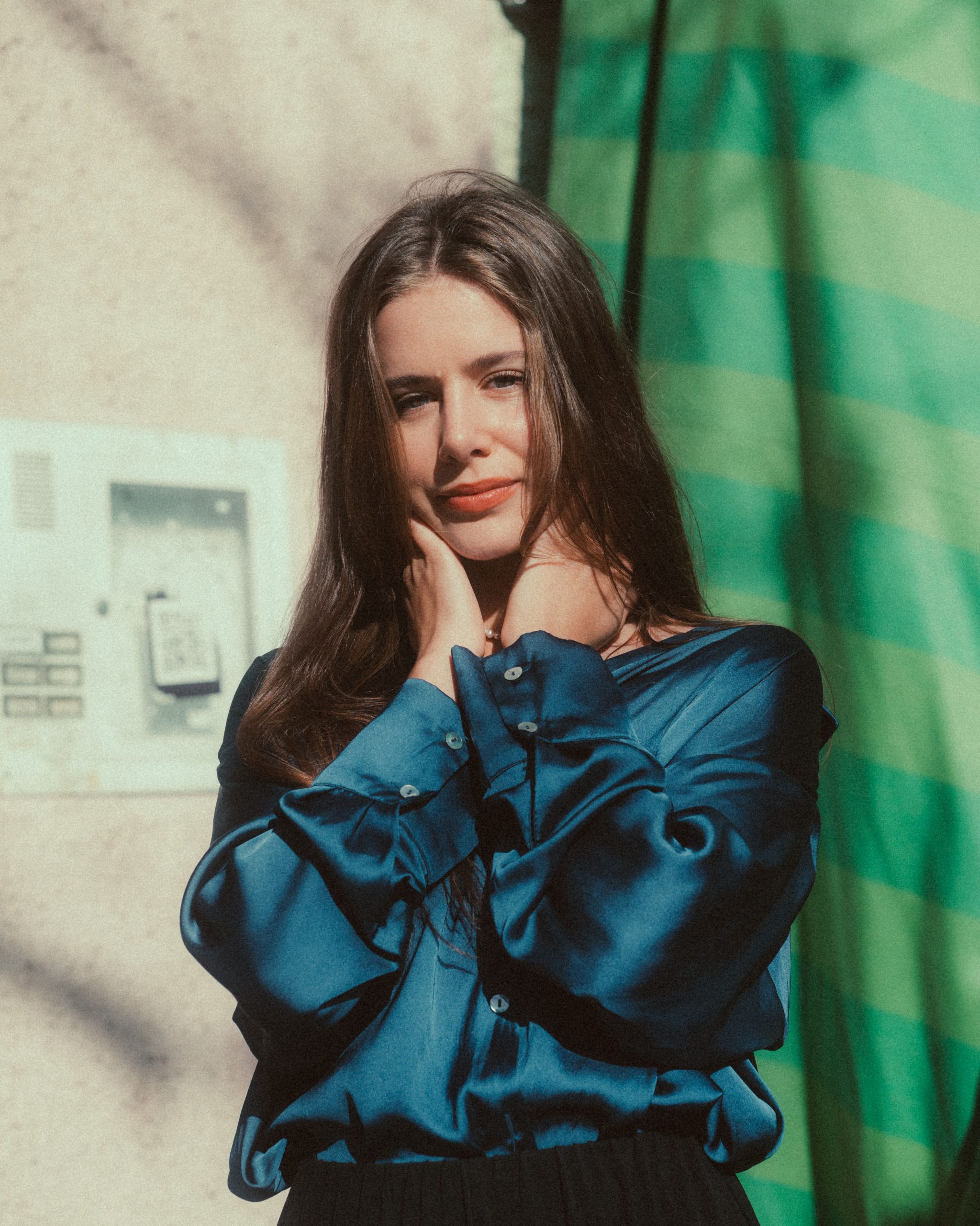 Woman modeling a blue satin blouse against a simple background
